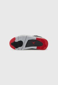 Semelle de basket noir et blanc avec un accent rouge, en caoutchouc texturé pour l'adhérence, et un panneau central noir avec un logo. Motif de semelle géométrique.