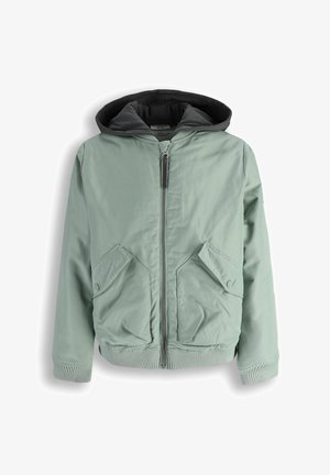 Jasnozielona kurtka na zamek z czarnym obszyciem kaptura, dwie przednie kieszenie z patkami i zatrzaskami oraz ściągacze na mankietach i u dołu.