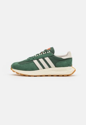 Grüner und weißer Sportschuh mit drei weißen Streifen an der Seite und einer hellbraunen Gummisohle, von der Außenseite betrachtet.