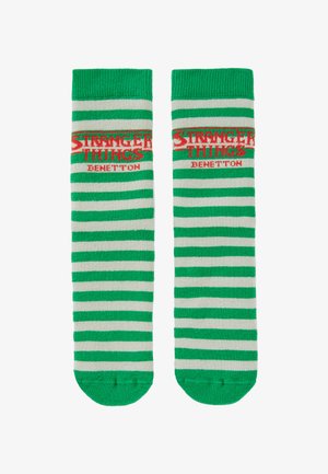 Calcetines a rayas verdes y blancas con las palabras "STRANGER THINGS" y "BENETTON" en letras rojas, con puños acanalados y textura suave.