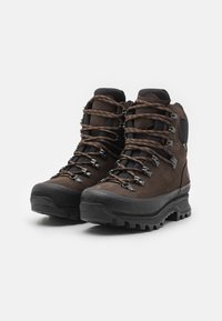Brune lær hiking støvler med metaløjer, tykke snørebånd og en robust sort gummisål. Forstærket tå og ankelstøtte.