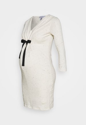 Cremefarbenes Umstandskleid mit langen Ärmeln, gesprenkeltem Muster, Wickel-V-Ausschnitt und schwarzer Taillenschleife, auf weißem Hintergrund dargestellt.