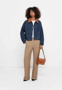 Spijkerjack met een bruine corduroy kraag, twee voorzakken, gecombineerd met beige broek en een bruine schoudertas. Eenvoudig ontwerp, blauwe kleur.