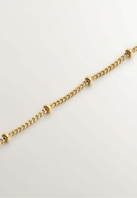 Pulsera de cadena de oro con eslabones interconectados y acentos redondeados lisos espaciados uniformemente a lo largo del diseño. Textura pulida.