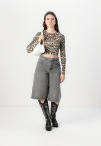Leopard print long-sleeve crop top, gray wide-leg jeans, black knee-high boots with white embroidery, carrying a white handbag.