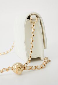 White leather handbag with a curved shape, featuring a golden chain strap and clasp. Surface has a textured pattern.