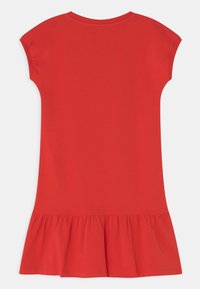 Robe rouge à manches courtes en tissu doux, dotée d'un volant évasé à l'ourlet et d'un décolleté rond simple.