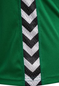 Zielony strój sportowy z czarno-białym wzorem z chevronem po bokach, wykonany z teksturowanej, oddychającej tkaniny i wzmocnionymi szwami.