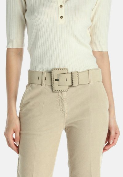 Bež široki pojas s velikom pravokutnom kopčom, s prošivenim detaljima i glatkom teksturom, nošen preko svijetlih kadrovskih hlača.