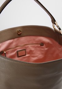 Bolso tote de cuero marrón con una textura suave, que cuenta con un interior de satén rosa, un bolsillo con cremallera y detalles en hardware dorado.