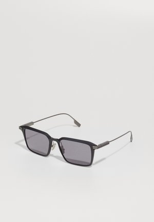 Black rectangular sunglasses with dark lenses, metal accents, and slender arms. Frame features a matte texture and angular design.