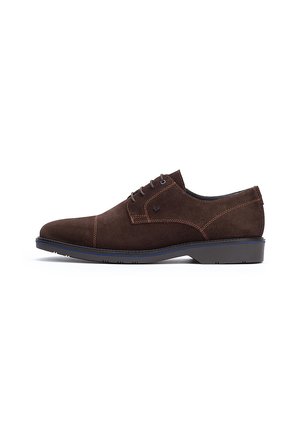 Zapatos de gamuza marrón con cordones, con costuras en contraste, puntera redondeada y suela plana de goma. Diseño minimalista con un detalle del logotipo en el costado.