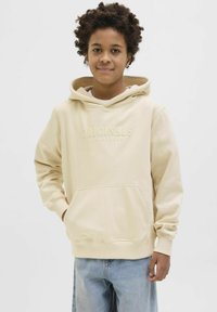 Bežs kapuce ar auklu, priekšējo kabatu un iespiedtextu "ORIGINALS." Izgatavots no mīksta auduma, ar ikdienišķu dizainu un brīvu piegriezumu.