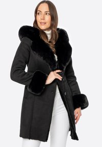 Czarny płaszcz z futrzanym kołnierzem i mankietami, o dopasowanym kroju, zapinany na guziki, o gładkiej fakturze. Białe tło.