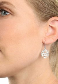 Pendientes de árbol de la vida de plata con un intrincado diseño recortado, forma circular y un delicado cierre de gancho. Acabado brillante y pulido.