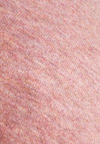 Tissu texturé dans une douce teinte rose pastel, présentant un subtil mélange de fils plus clairs et plus foncés, créant un aspect mélangé.