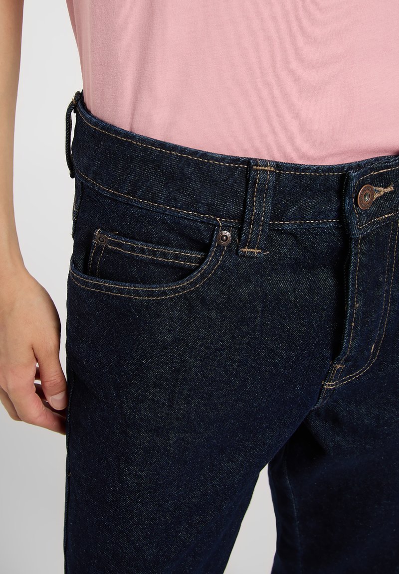 Navy blue denim jeans with a classic fit. Features include copper hardware, five-pocket design, and contrasting stitching along the seams.