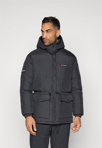 Casaco puffer preto com capuz, apresentando fecho éclair à frente, dois grandes bolsos frontais, punhos elásticos e um logótipo no peito e na manga.