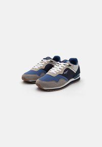 Sneakers featuring a combination of blue, grey, and navy materials. Textured suede and mesh, with white laces and a rubber sole.