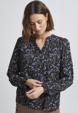 Blühendes Bluse in Navy mit weißen und goldenen Akzenten. Merkmale sind ein V-Ausschnitt, lange Ärmel mit gerafften Manschetten und einem strukturierten Stoff.