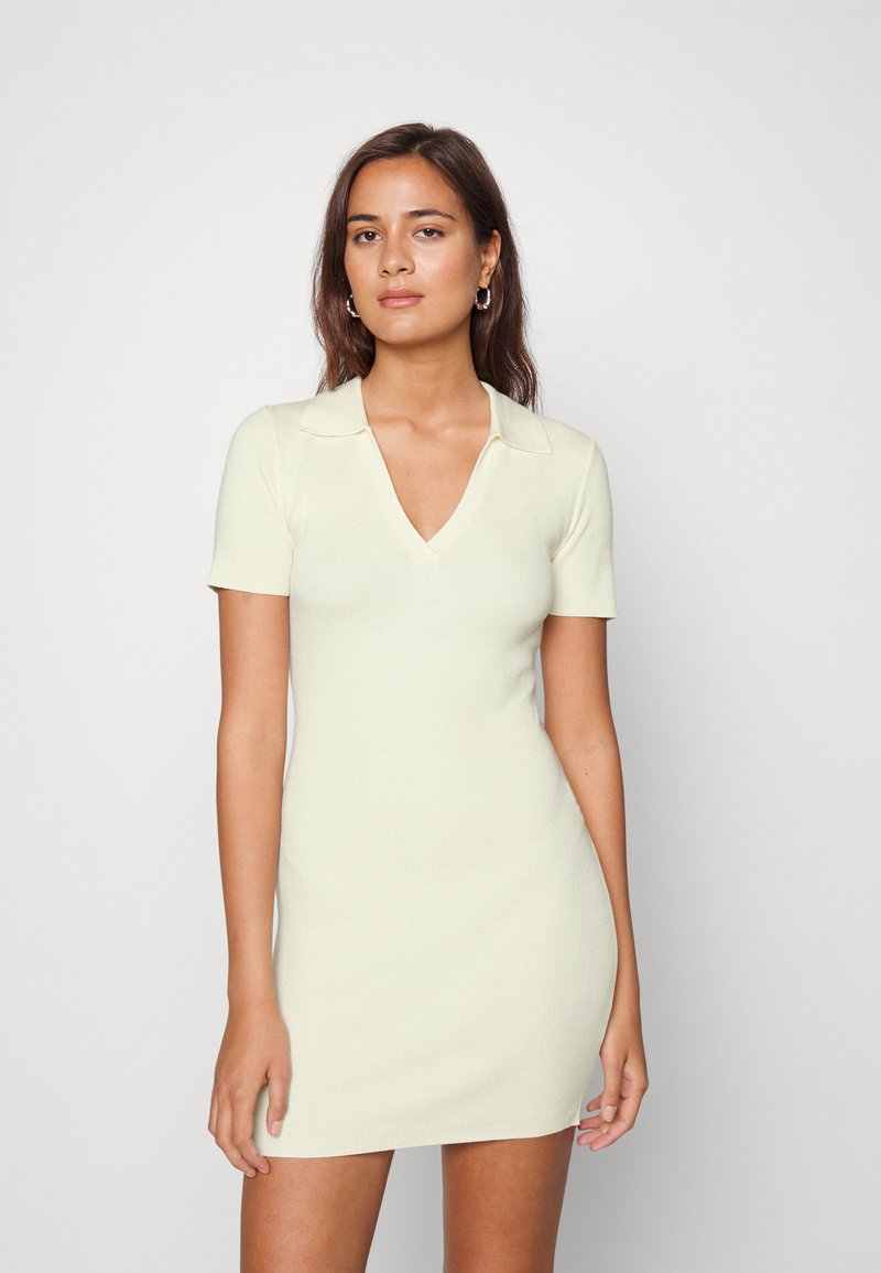 Vestido de malha de mangas curtas em amarelo claro com decote em V e detalhe de gola, apresentando uma forma ajustada e textura suave.