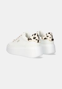 Zapatillas deportivas blancas de plataforma con un acabado suave, que presentan un acento de manchas en blanco y negro en el talón, y ojales en rosa dorado para los cordones.