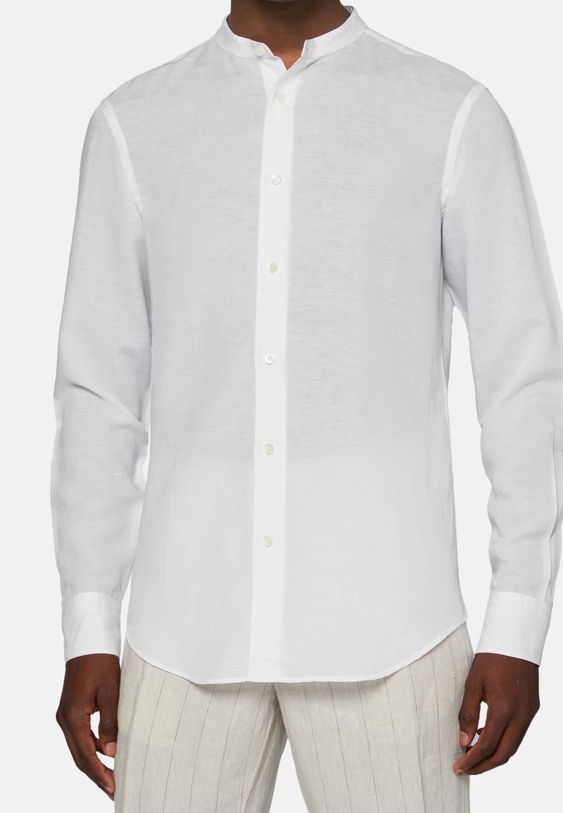 Camicia bianca a maniche lunghe realizzata in tessuto leggero. Presenta un colletto alla coreana, una patta frontale con bottoni e una vestibilità comoda. Superficie strutturata.