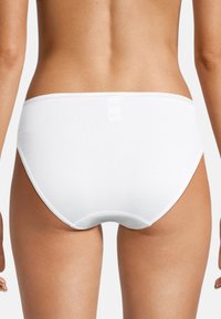 Weiße Baumwollslip mit glatter Textur und elastischem Bund. Verfügt über ein nahtloses Design und einen geschwungenen Rücken für Komfort und Passform.