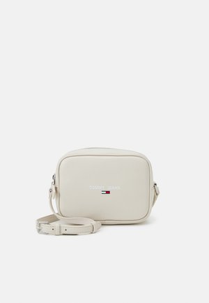 Lille rektangulær beige crossbody taske med justerbar rem, lynlåslukning og Tommy Jeans logo på fronten med rød, hvid og blå flagemblem.