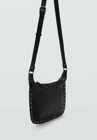 Borsa a tracolla in pelle nera con forma quadrata, dotata di chiusura con zip e borchie argentate lungo i bordi. Include una tracolla regolabile.