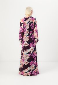 Maxime dresset sisältää tumman taustan, jossa on suuria vaaleanpunaisia, valkoisia ja violetteja kukkakuoseja, pitkät hihat ja kokoon kerätty yksityiskohta selässä.