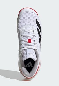 Baskets blanches avec tige en mesh, accents noirs et détails rouges sur la semelle. Elles sont dotées de lacets blancs et d'un col rembourré pour plus de confort.