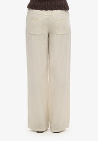 Pantaloni in lino a gamba larga color beige chiaro, con una morbida texture, due tasche posteriori e una leggera caduta. Vita elasticizzata per il massimo comfort.