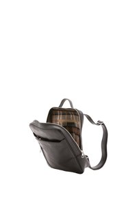 Zaino in pelle nera con chiusura a cerniera, dotato di una fodera interna a quadretti e spallacci regolabili. Include una tasca frontale e un design slanciato.