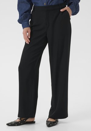 Black wide-leg trousers made from smooth fabric, featuring a high waist, side pockets, and a relaxed fit. Paired with black flats.