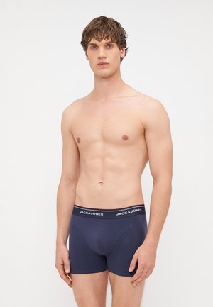 Tumši jūraszila bokseru apakšveļa ar platāku jostu, uz kuras rakstīts "JACK & JONES" baltā krāsā. Mīksts materiāls un pieguļošs siluets.