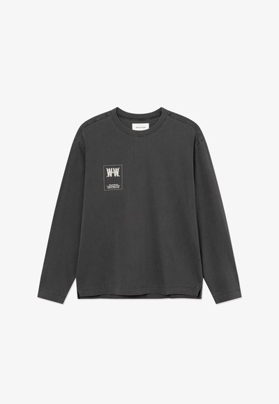 Chemise à manches longues gris foncé avec col rond, comportant un petit motif blanc et du texte sur la partie gauche de la poitrine.
