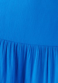 Un vestido azul brillante con una superficie texturizada, que presenta detalles plisados en el dobladillo y un cuerpo liso. La tela parece ligera y fluida.