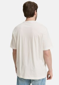 Witte T-shirt met korte mouwen, een relaxte pasvorm, ronde halslijn en een zachte textuur, gecombineerd met lichtblauwe denim jeans.