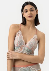Lace bralette in soft peach and mint with floral embroidery, scalloped edges, and adjustable straps; sheer design highlights intricate patterns.