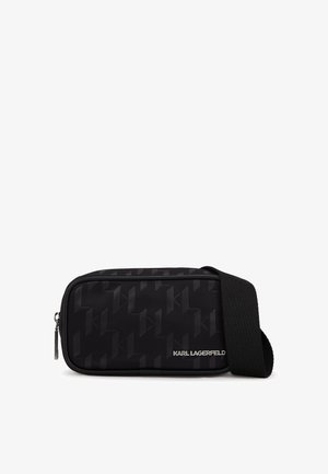 Melns somiņas ar rāvējslēdzēju un teksturētu ģeometrisku rakstu. Izgatavota no gludas sintētiskas materiāla un ar regulējamu auduma siksnu. Rādīts Karls Lāgerfelds logos.