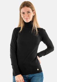 Maglione nero a collo alto con maniche lunghe, polsini e orlo a coste, con un piccolo dettaglio del logo in vita. Texture liscia.