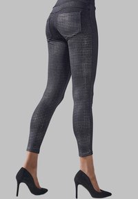 Leggings neri con motivo a stampa, realizzati in tessuto elastico, con un design a scacchi texturizzato, abbinati a tacchi alti neri.