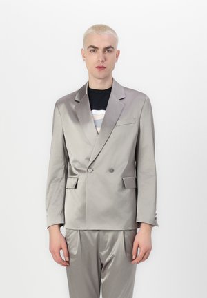 Chaqueta de traje de satén plateado con cierre de doble botonadura, solapas con muesca, bolsillos laterales con solapa y una textura suave, combinada con pantalones a juego.