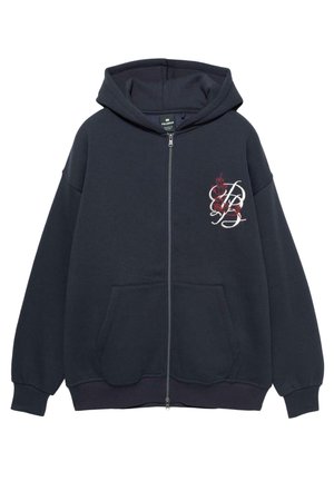 Hanorac zip-up de culoare bleu închis, cu buzunare frontale, glugă și un design floral brodat în roșu și alb pe partea stângă a pieptului.