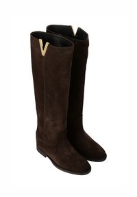 Bottes cuissardes en daim marron avec un design droit, un talon plat et un accent doré en forme de V sur le bord supérieur. Texture douce, sans fermetures visibles.