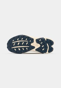 Semelle de chaussure Hoka avec un crampon profond et structuré ; caoutchouc bleu marine et semelle intermédiaire crème ; surface texturée pour une adhérence et une stabilité optimales.