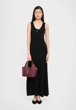 Abito nero senza maniche con scollo tondo e piccolo dettaglio di fiocco nero, abbinato a una borsa bordeaux e scarpe nere a punta.