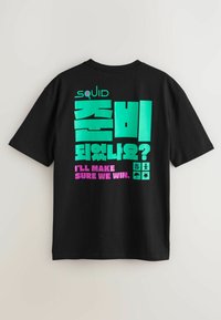 Tricou negru cu text îndrăzneț și reflectorizant în verde, roz și alb. Designul include caractere coreene și simboluri legate de tematica unui joc.