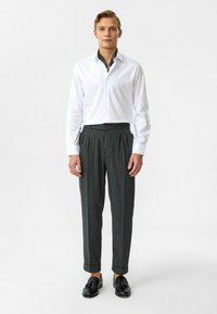 Witte overhemd met knopen en een patroon op de kraag, gecombineerd met grijze broek met streepjes, en zwarte schoenen. Gestructureerd ontwerp en smalle pasvorm.
